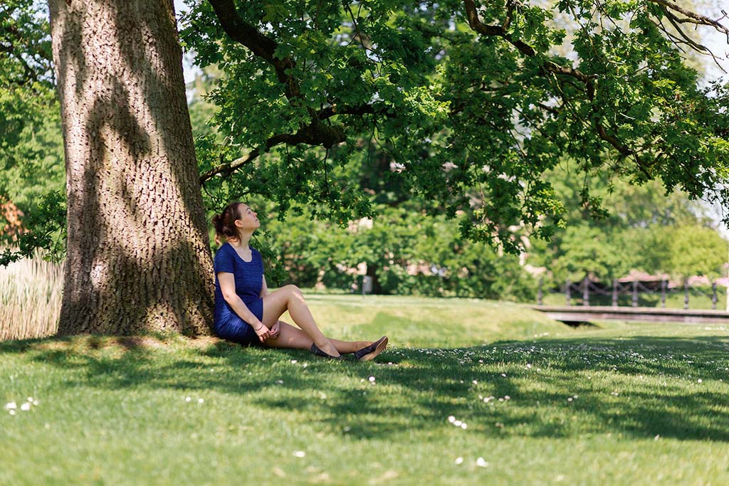 Breathworks coach Lisanne van Niekerk relaxing in the shade under a tree in a green park in Den Bosch